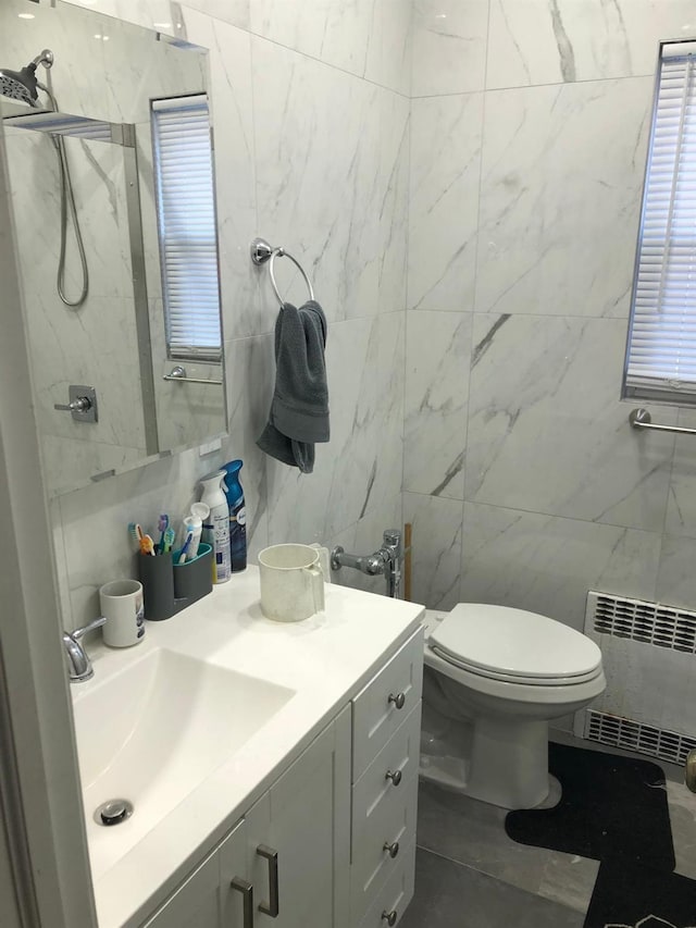 bathroom featuring radiator, vanity, tile walls, and toilet