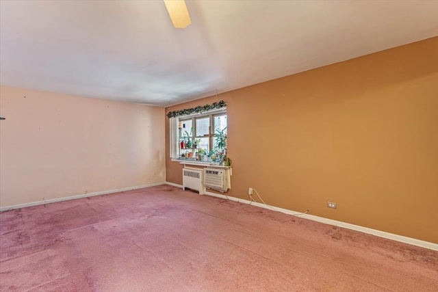 carpeted spare room featuring a wall mounted air conditioner and radiator heating unit