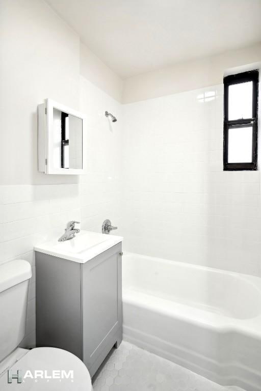 full bathroom with vanity, tile walls, tile patterned flooring, toilet, and tiled shower / bath