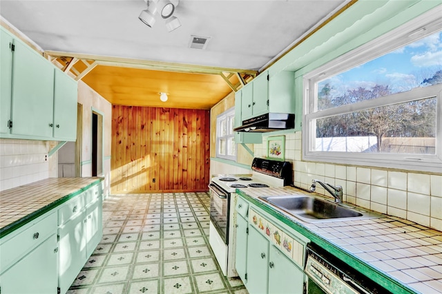 kitchen with green cabinets, electric stove, sink, tile counters, and dishwashing machine