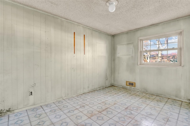 spare room featuring a textured ceiling and wooden walls