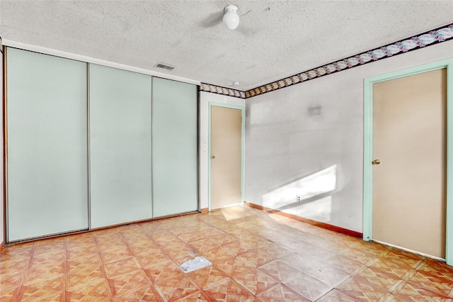 unfurnished bedroom featuring a textured ceiling and a closet