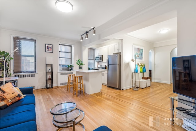 living room with radiator heating unit, light wood-type flooring, and ornamental molding