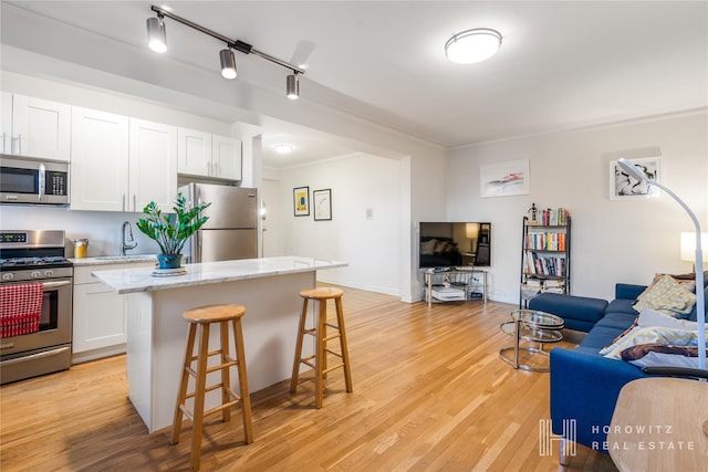 kitchen featuring white cabinets, a kitchen breakfast bar, sink, appliances with stainless steel finishes, and a kitchen island