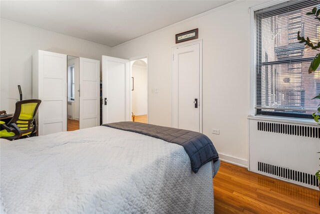 bedroom featuring radiator heating unit and hardwood / wood-style floors