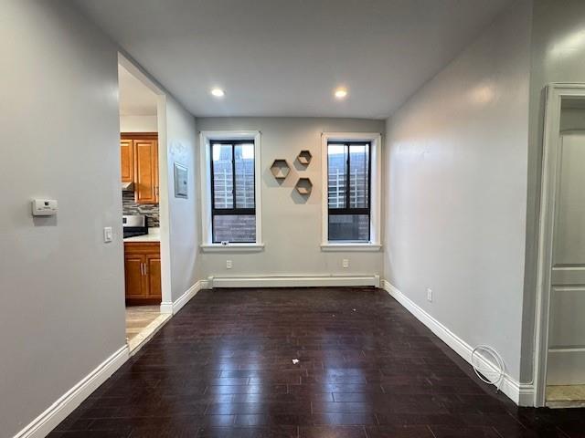 unfurnished dining area with dark hardwood / wood-style flooring and a baseboard heating unit