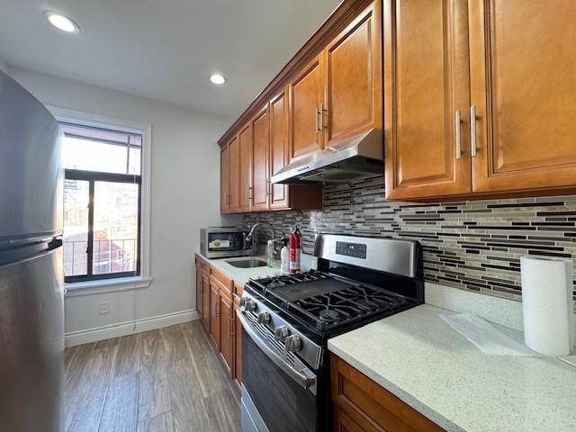 kitchen featuring tasteful backsplash, a wealth of natural light, stainless steel appliances, sink, and wood-type flooring