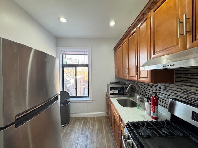 kitchen featuring sink, light wood-type flooring, stainless steel appliances, and tasteful backsplash