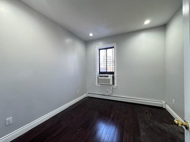 spare room with cooling unit, dark hardwood / wood-style floors, and a baseboard heating unit