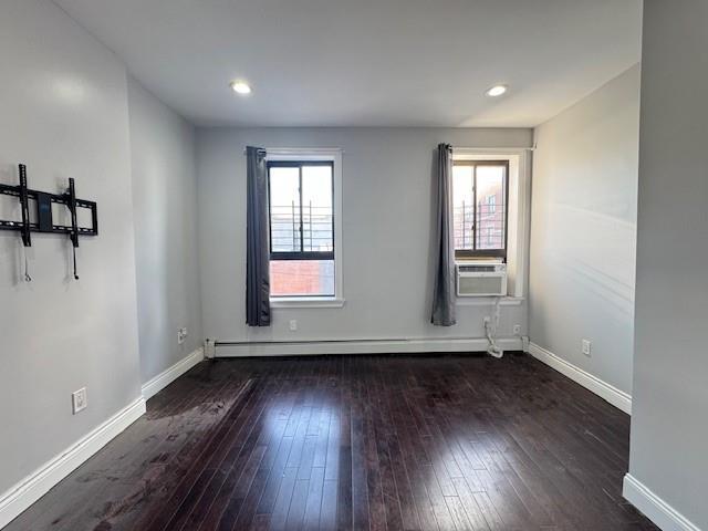 unfurnished room featuring baseboard heating, cooling unit, and dark hardwood / wood-style floors