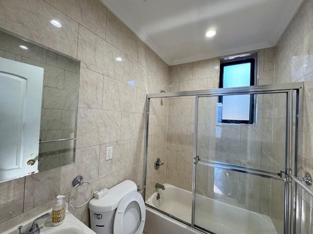 bathroom featuring crown molding, toilet, bath / shower combo with glass door, and tile walls