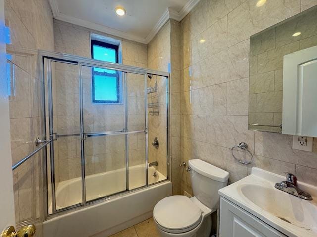 full bathroom with tile patterned floors, toilet, shower / bath combination with glass door, vanity, and tile walls