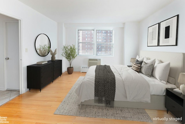 bedroom with a wall mounted air conditioner and light hardwood / wood-style floors