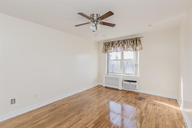 unfurnished room featuring a wall mounted AC, ceiling fan, radiator heating unit, and light wood-type flooring