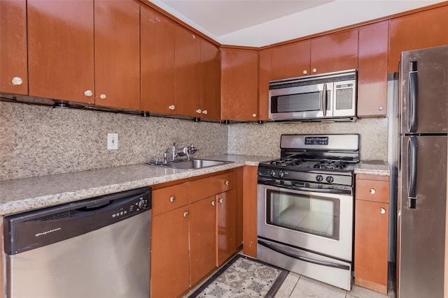 kitchen with backsplash, sink, light stone countertops, light tile patterned floors, and appliances with stainless steel finishes