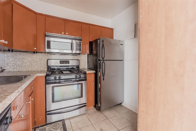 kitchen featuring appliances with stainless steel finishes, tasteful backsplash, light tile patterned floors, and sink