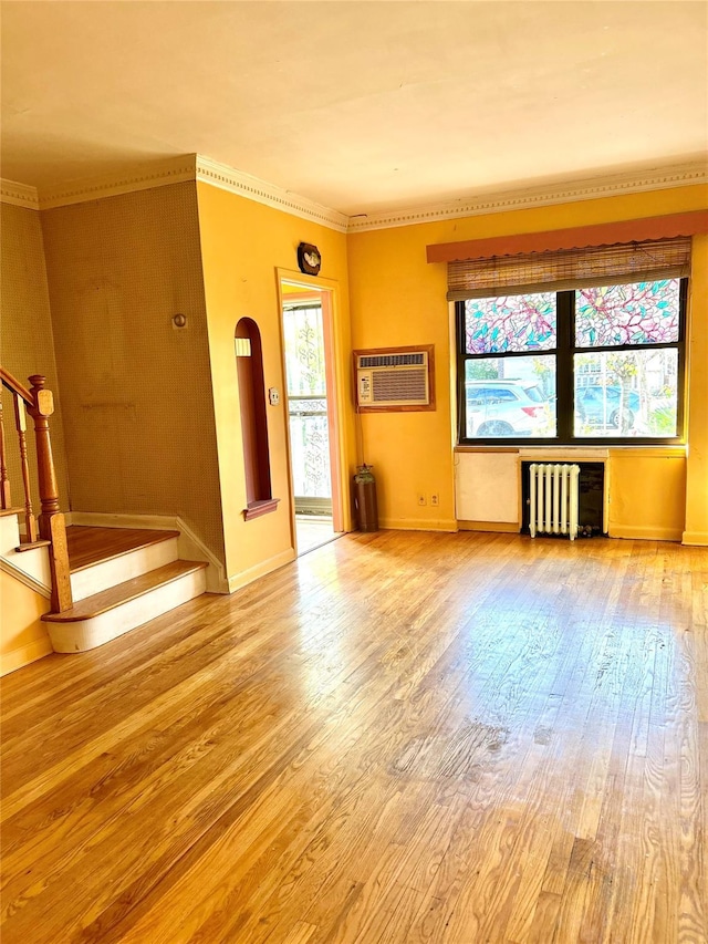 unfurnished living room featuring plenty of natural light, radiator, a wall unit AC, and light hardwood / wood-style flooring