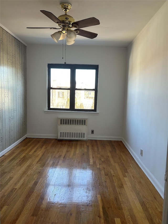 empty room with ceiling fan, radiator heating unit, and dark hardwood / wood-style floors