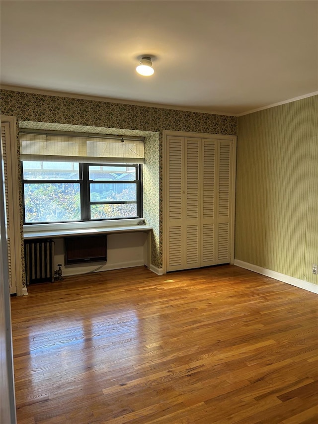 empty room featuring hardwood / wood-style floors, radiator heating unit, and crown molding