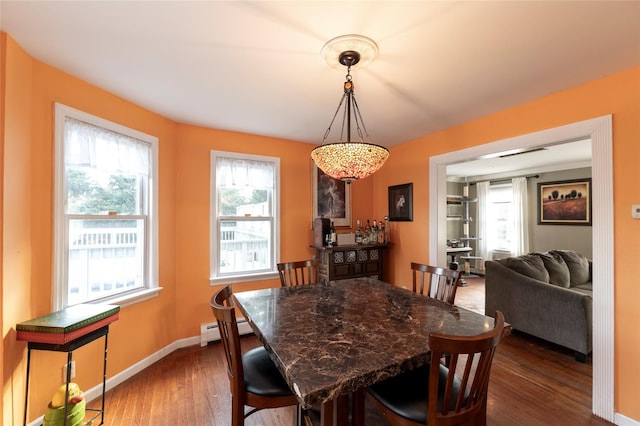 dining room featuring plenty of natural light, baseboard heating, and dark wood-type flooring