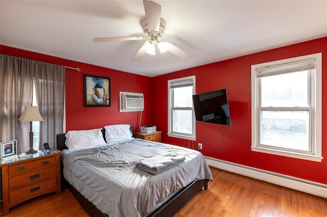 bedroom featuring hardwood / wood-style flooring, ceiling fan, a wall mounted AC, and a baseboard heating unit