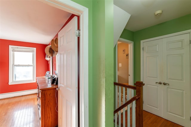 hallway with light wood-type flooring and a baseboard heating unit