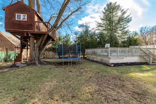 view of yard with a trampoline and a wooden deck