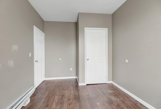 unfurnished bedroom featuring hardwood / wood-style flooring and a baseboard heating unit