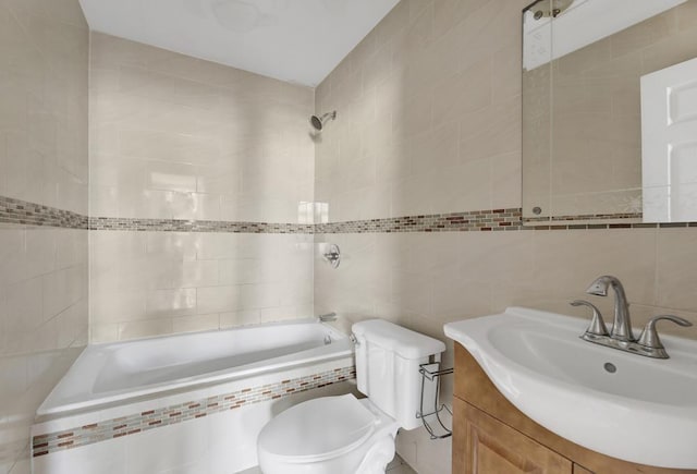 full bathroom featuring tiled shower / bath, vanity, tile walls, and toilet