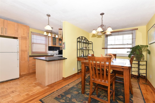 dining space featuring light parquet flooring and a notable chandelier