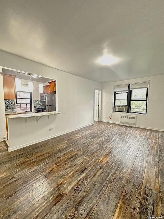 unfurnished living room with a wall mounted air conditioner and dark wood-type flooring