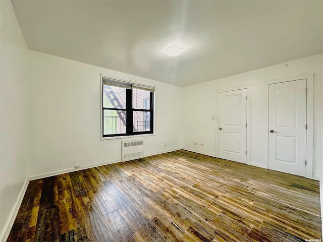 unfurnished bedroom featuring radiator heating unit and wood-type flooring