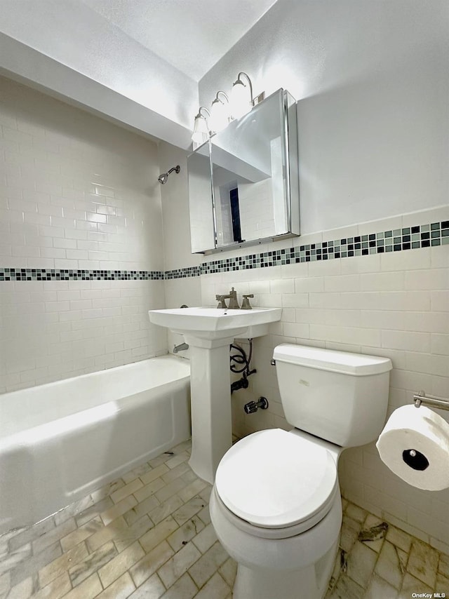 bathroom with tiled shower / bath, toilet, and tile walls