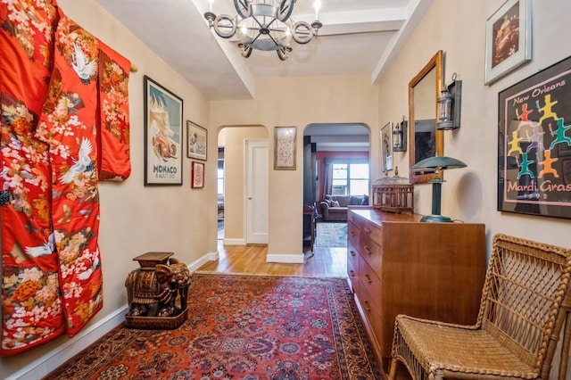 hall with wood-type flooring and an inviting chandelier