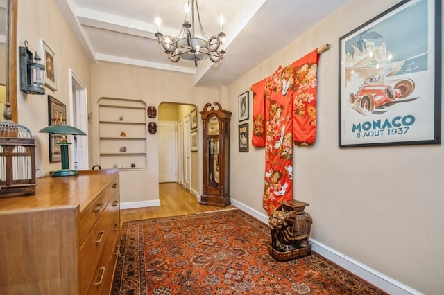 hall with light hardwood / wood-style flooring and a notable chandelier