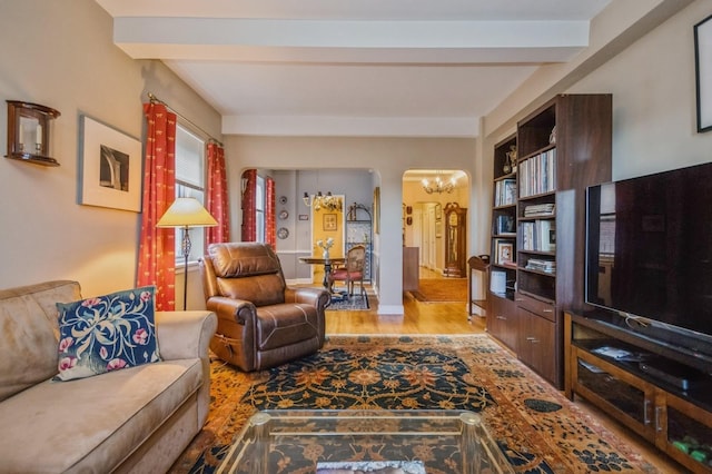 living room featuring beamed ceiling, light wood-type flooring, and an inviting chandelier