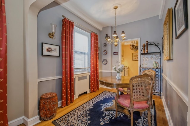 dining room featuring hardwood / wood-style floors, an inviting chandelier, and radiator