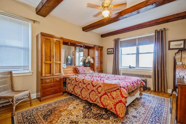 bedroom with ceiling fan, light hardwood / wood-style floors, radiator heating unit, and beam ceiling