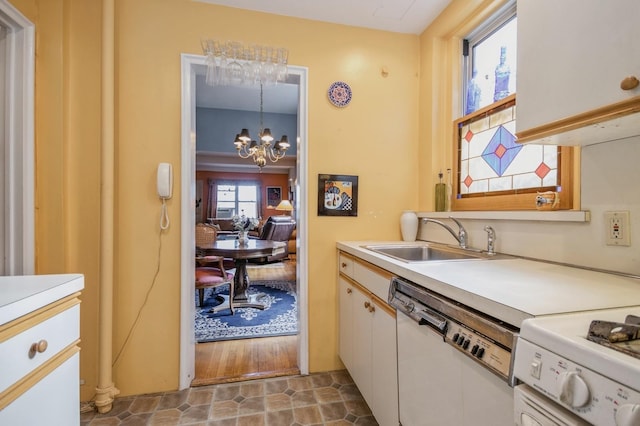 kitchen featuring pendant lighting, white appliances, sink, white cabinetry, and a chandelier