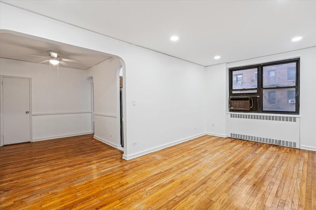 spare room with ceiling fan, light hardwood / wood-style floors, and radiator