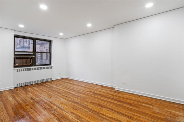 unfurnished room featuring hardwood / wood-style flooring, radiator, and cooling unit