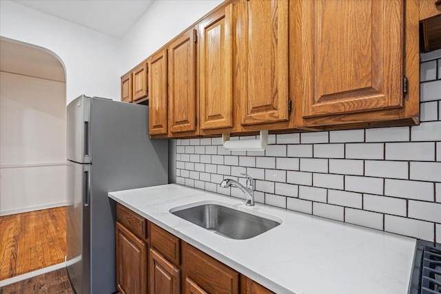 kitchen with dark hardwood / wood-style flooring, backsplash, stainless steel refrigerator, and sink