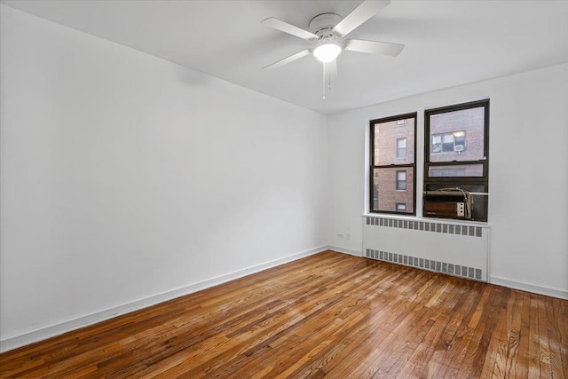 spare room with hardwood / wood-style floors, radiator, and ceiling fan