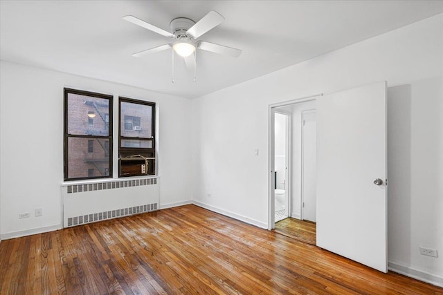 unfurnished room featuring hardwood / wood-style floors, ceiling fan, and radiator heating unit