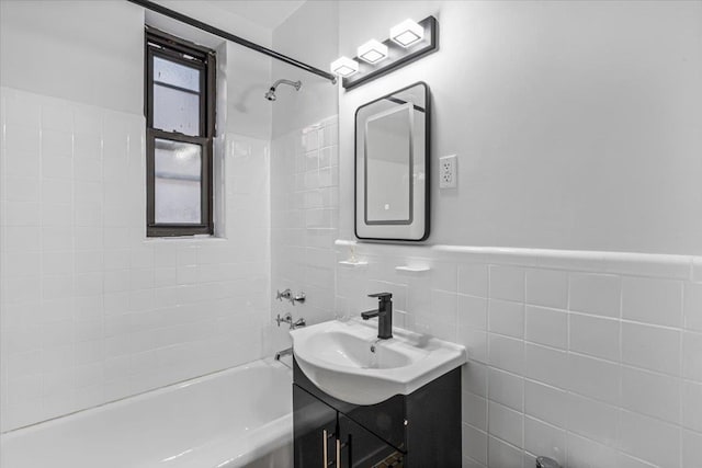 bathroom with vanity, tiled shower / bath, and tile walls