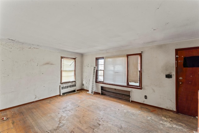 spare room featuring hardwood / wood-style flooring, radiator, and ornamental molding