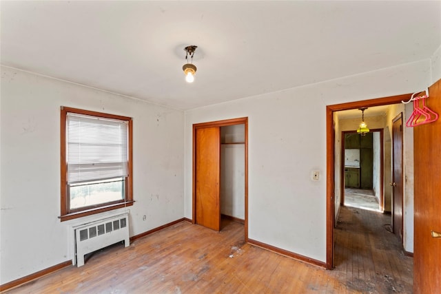 unfurnished bedroom featuring radiator heating unit, hardwood / wood-style flooring, and a closet