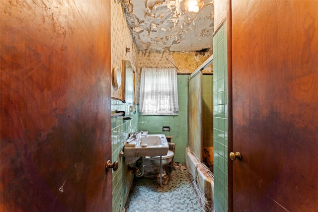 bathroom with tile patterned flooring, sink, and bath / shower combo with glass door