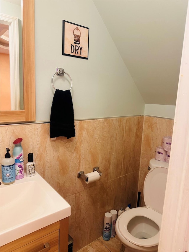 bathroom with tile patterned floors, vanity, toilet, and lofted ceiling