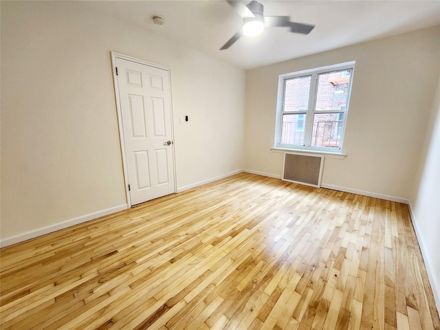 spare room featuring radiator, ceiling fan, and light hardwood / wood-style flooring